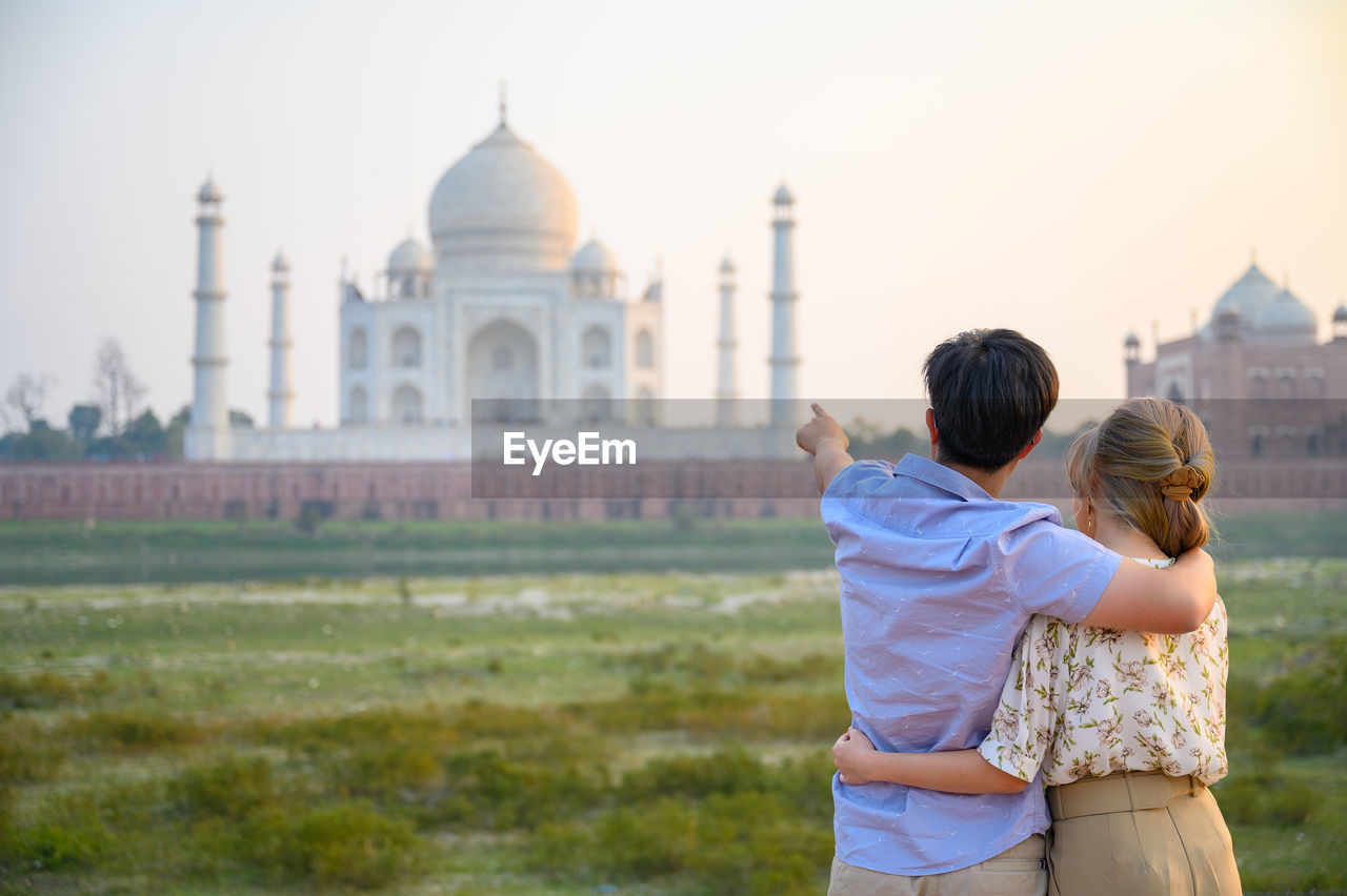 Rear view of couple standing against taj mahal