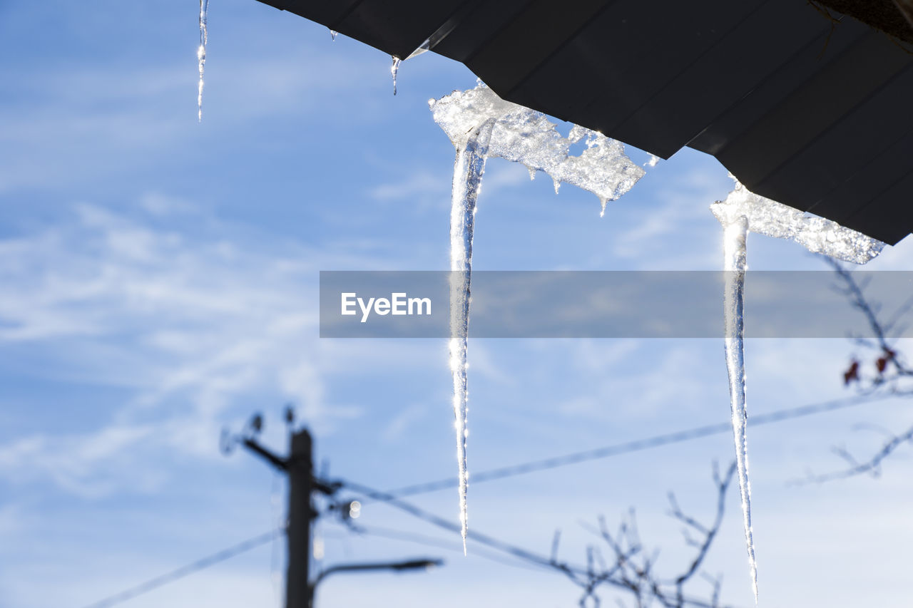 Icicles on the roof, blue sky and iced water, winter ice