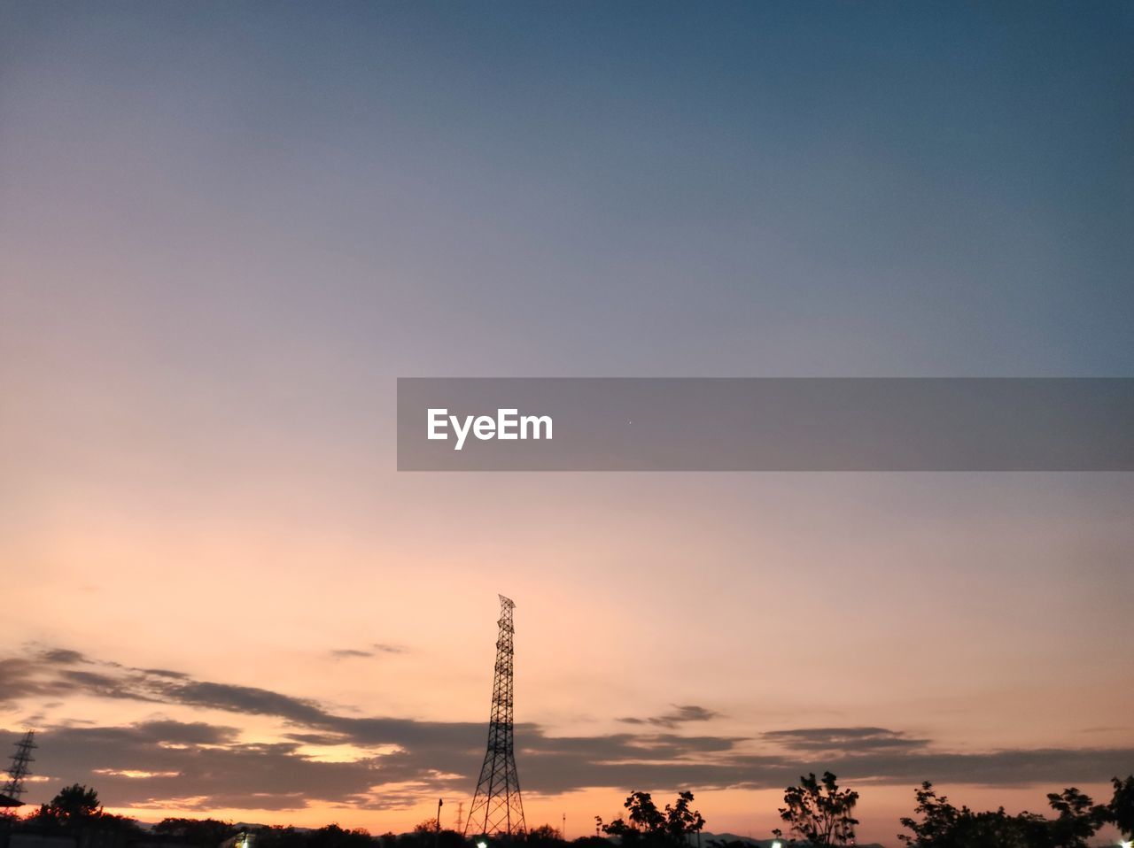 Low angle view of electricity pylon against sky during sunset