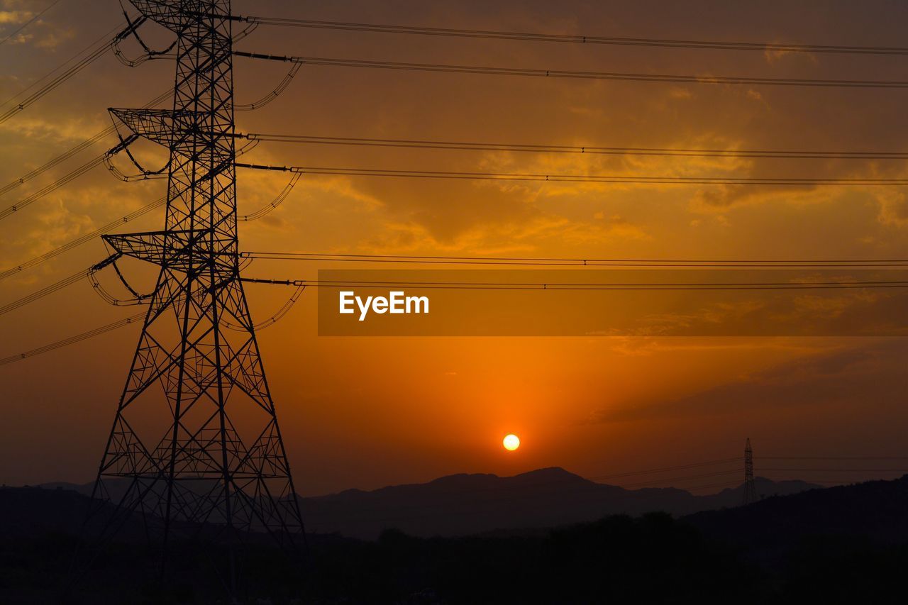 SILHOUETTE ELECTRICITY PYLONS AGAINST ORANGE SKY