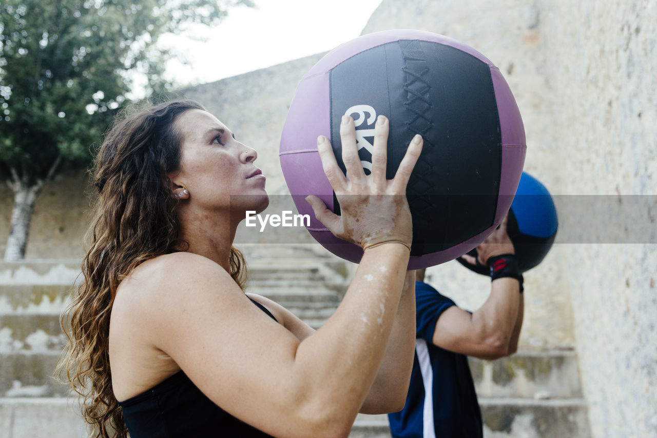 Couple throwing a medicine ball on a wall to practice crossfit.