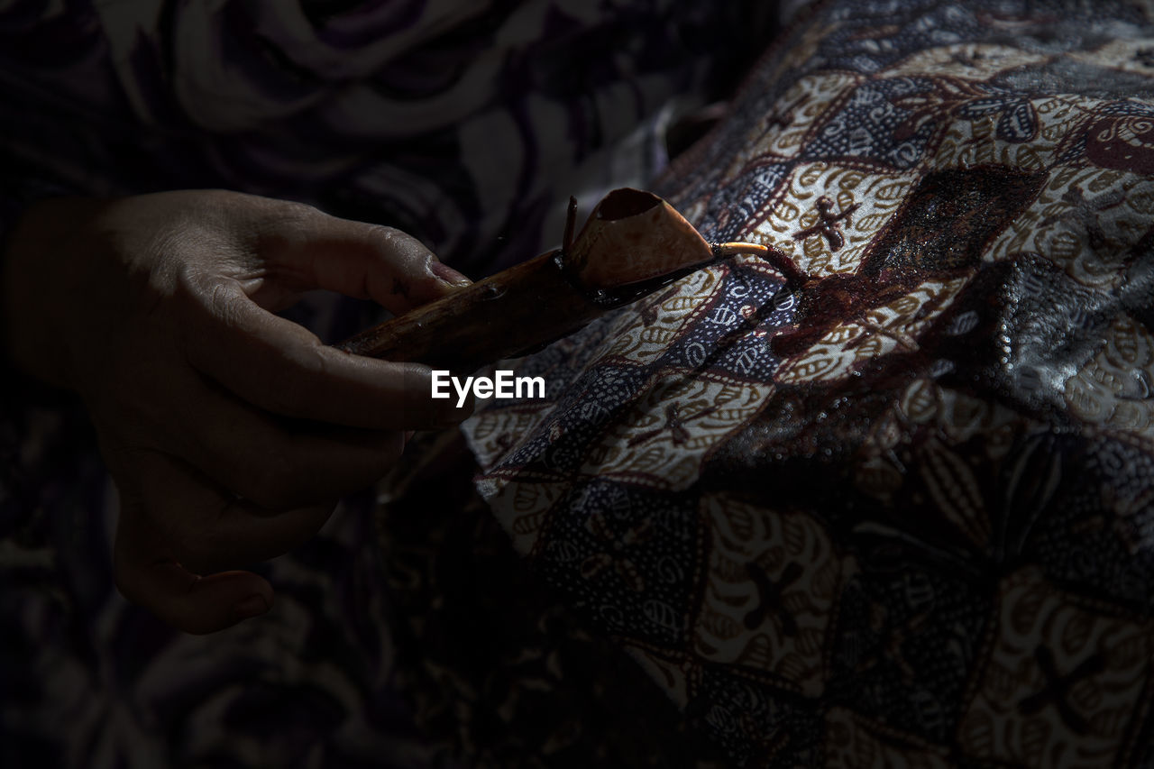 Cropped hand of craftsperson making batik at workshop