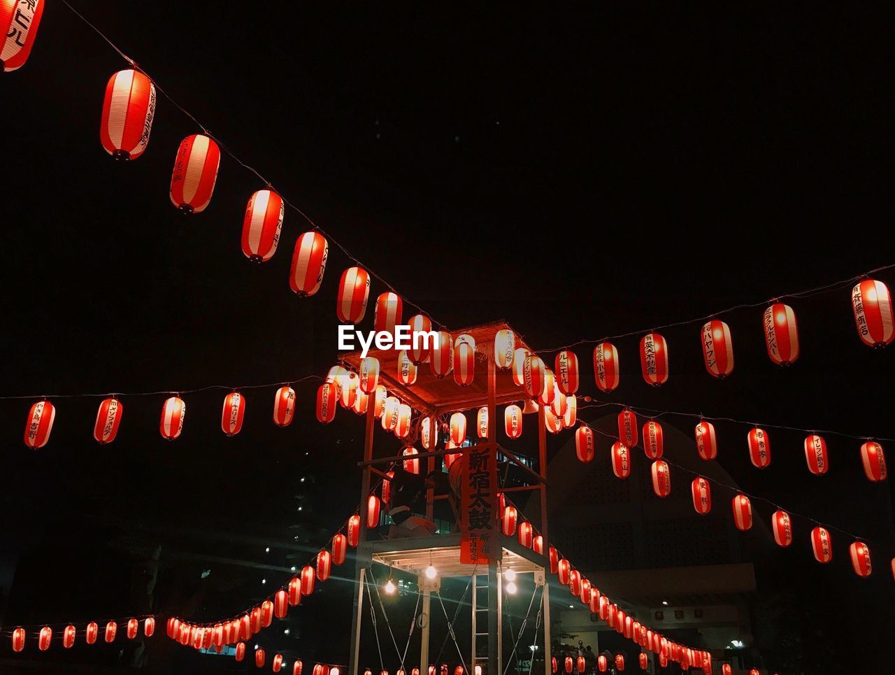 Low angle view of illuminated lanterns hanging against sky at night