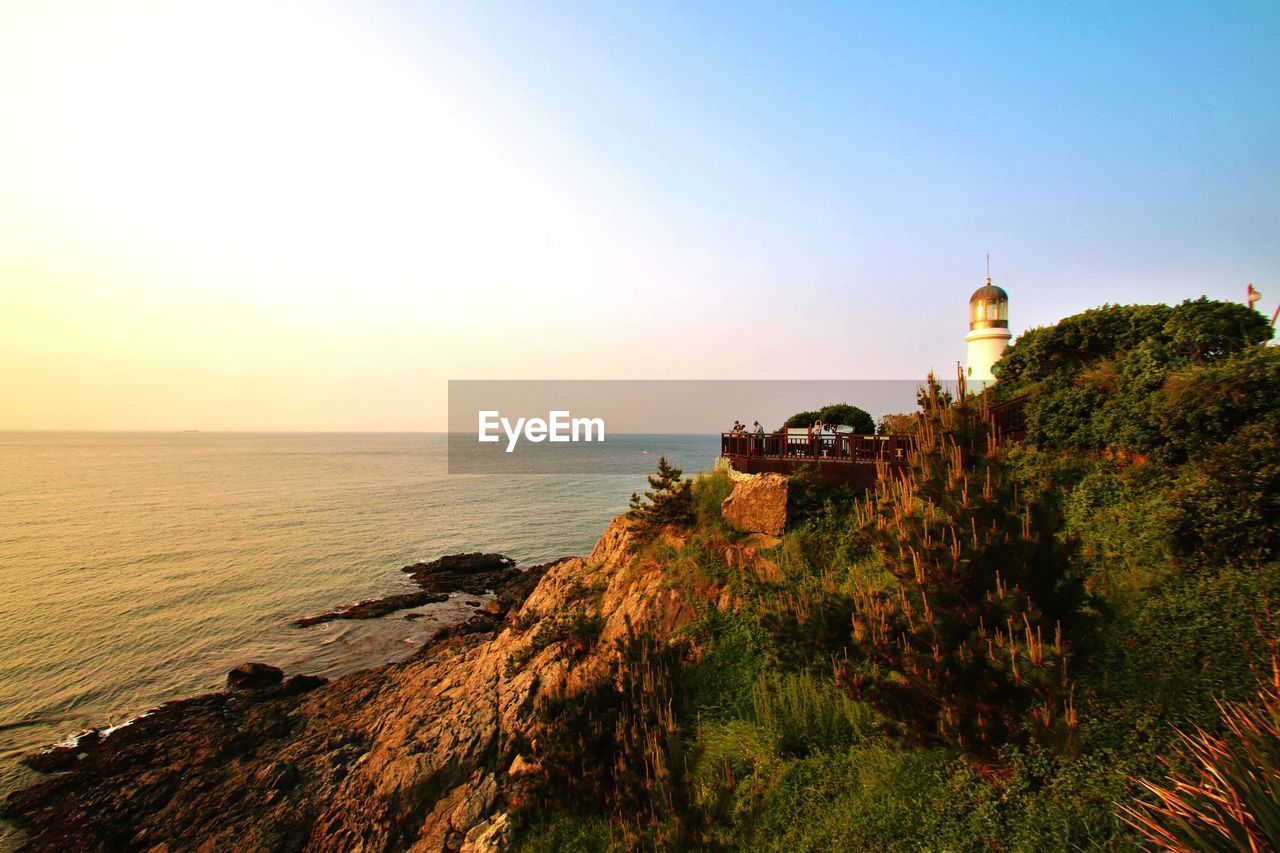 Scenic view of sea by cliff against clear sky during sunset