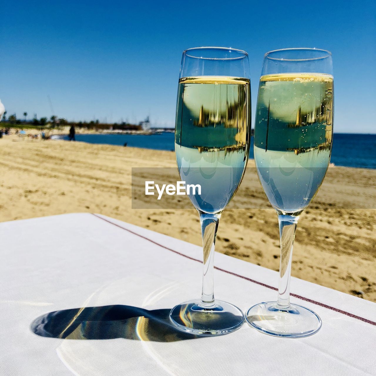 Wine glasses on table at beach against sky