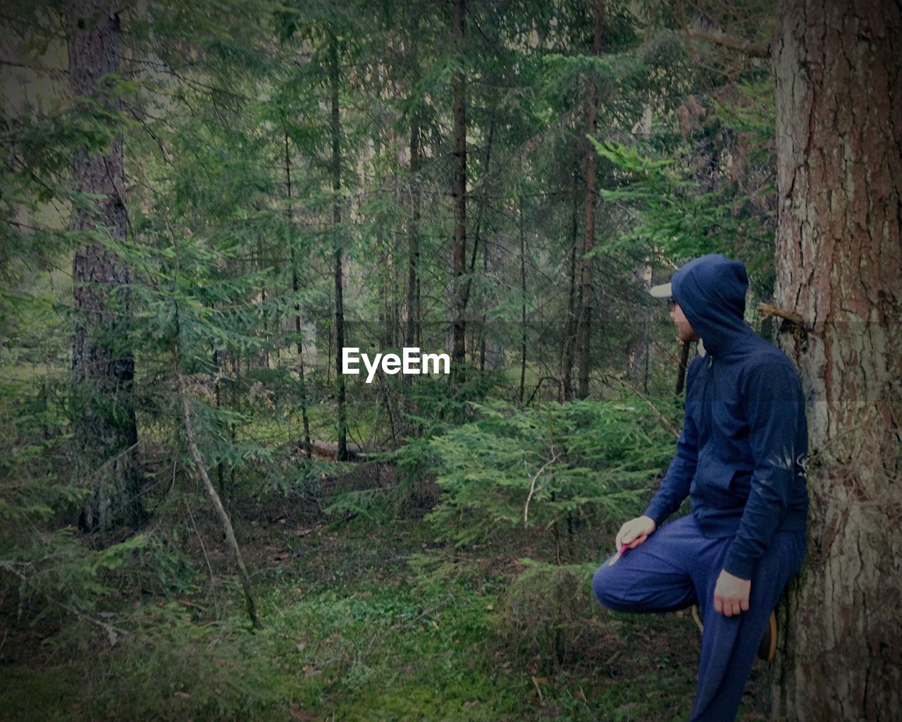 Person in hooded shirt standing in forest