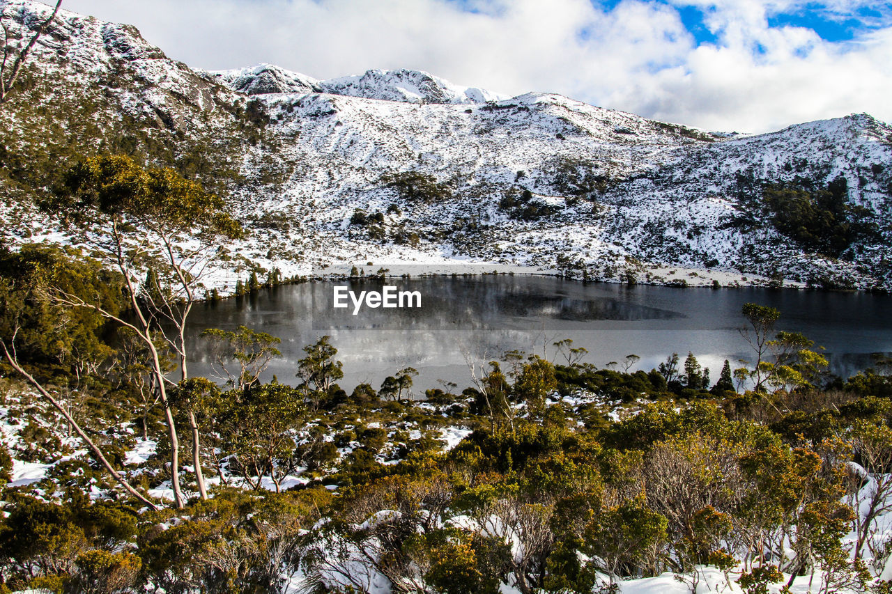 Scenic view of lake by snowcapped mountains against sky