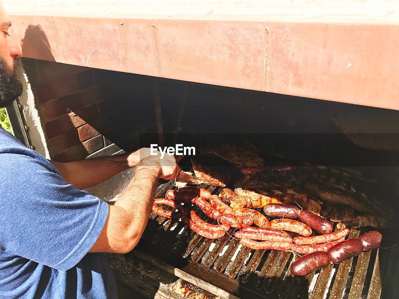 HIGH ANGLE VIEW OF MAN PREPARING FOOD ON BARBECUE