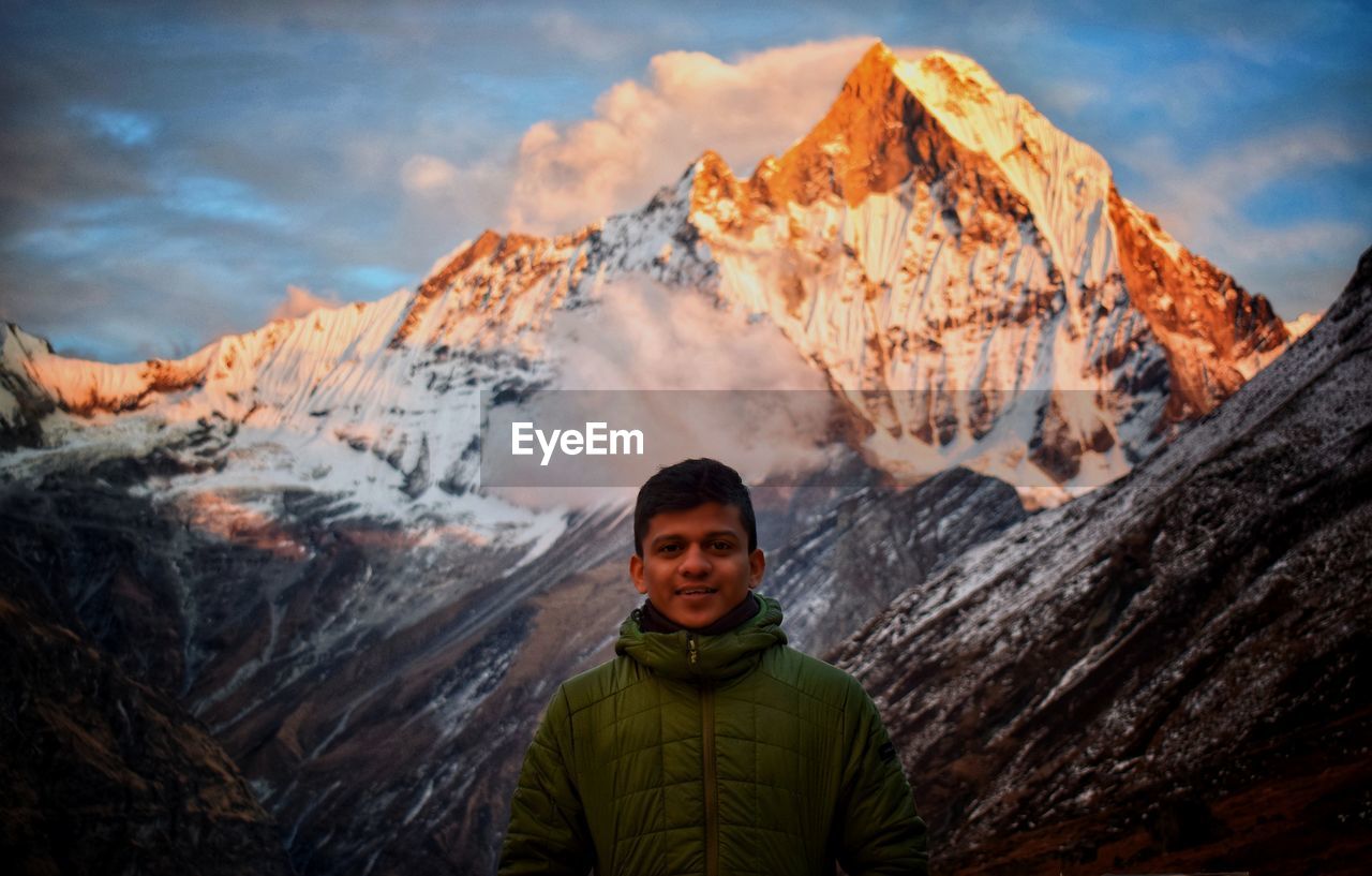 Portrait of man standing against snowcapped mountains 