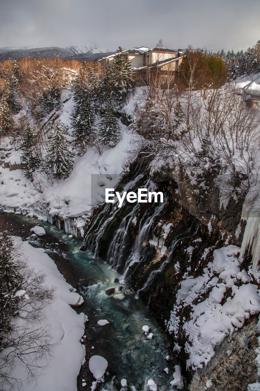 SCENIC VIEW OF RIVER FLOWING THROUGH SNOW COVERED LAND