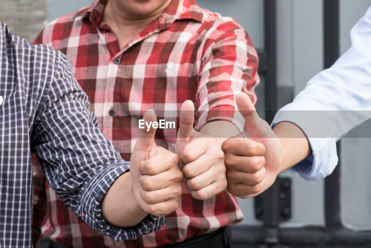 Close-up of men gesturing thumbs up sign