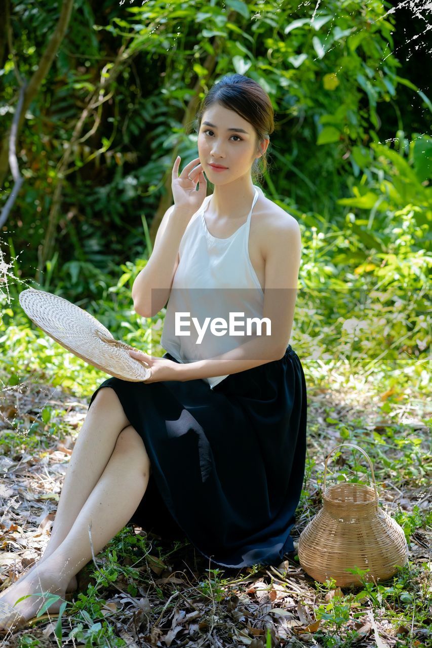 Side view of young woman sitting on field