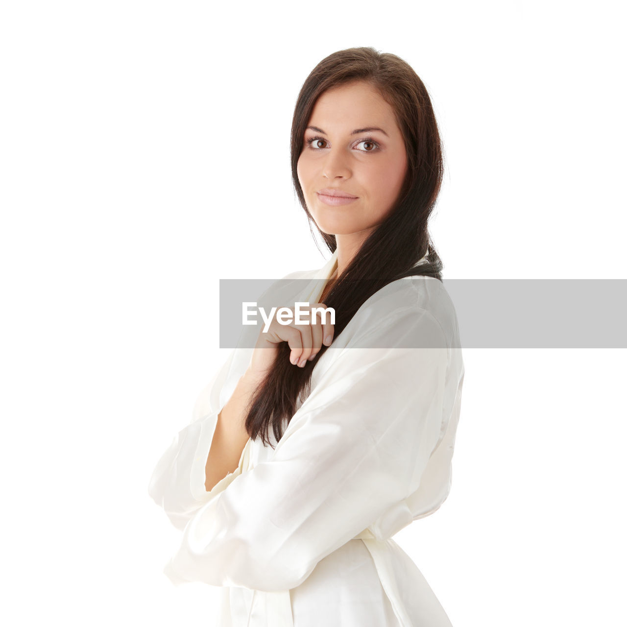 Portrait of smiling young woman holding hair while standing against white background