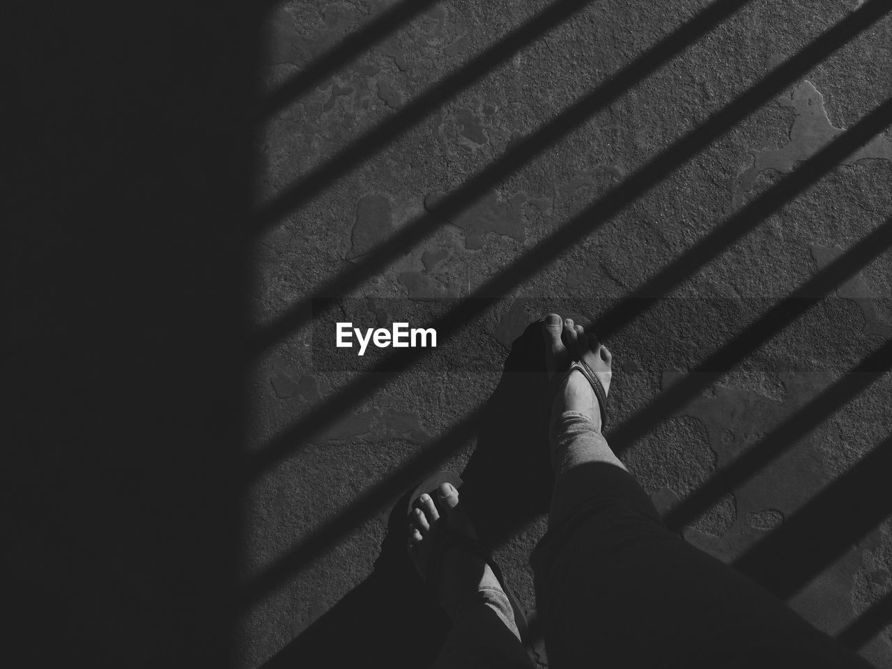 LOW SECTION OF PERSON SHADOW ON TILED FLOOR