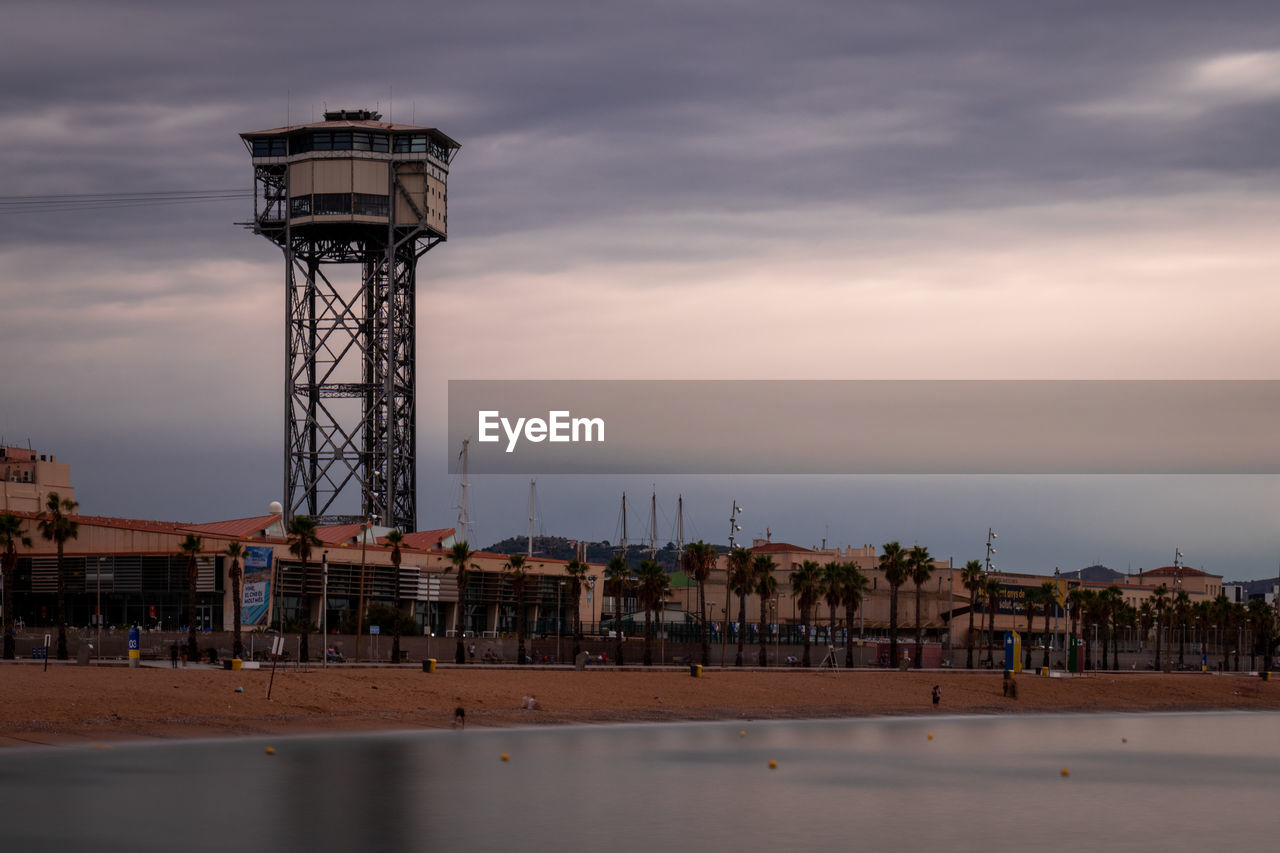 Tower on pier by sea against sky at sunset