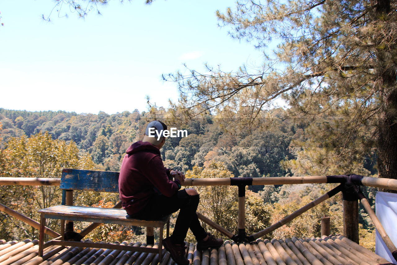 Man looking away while sitting on bench