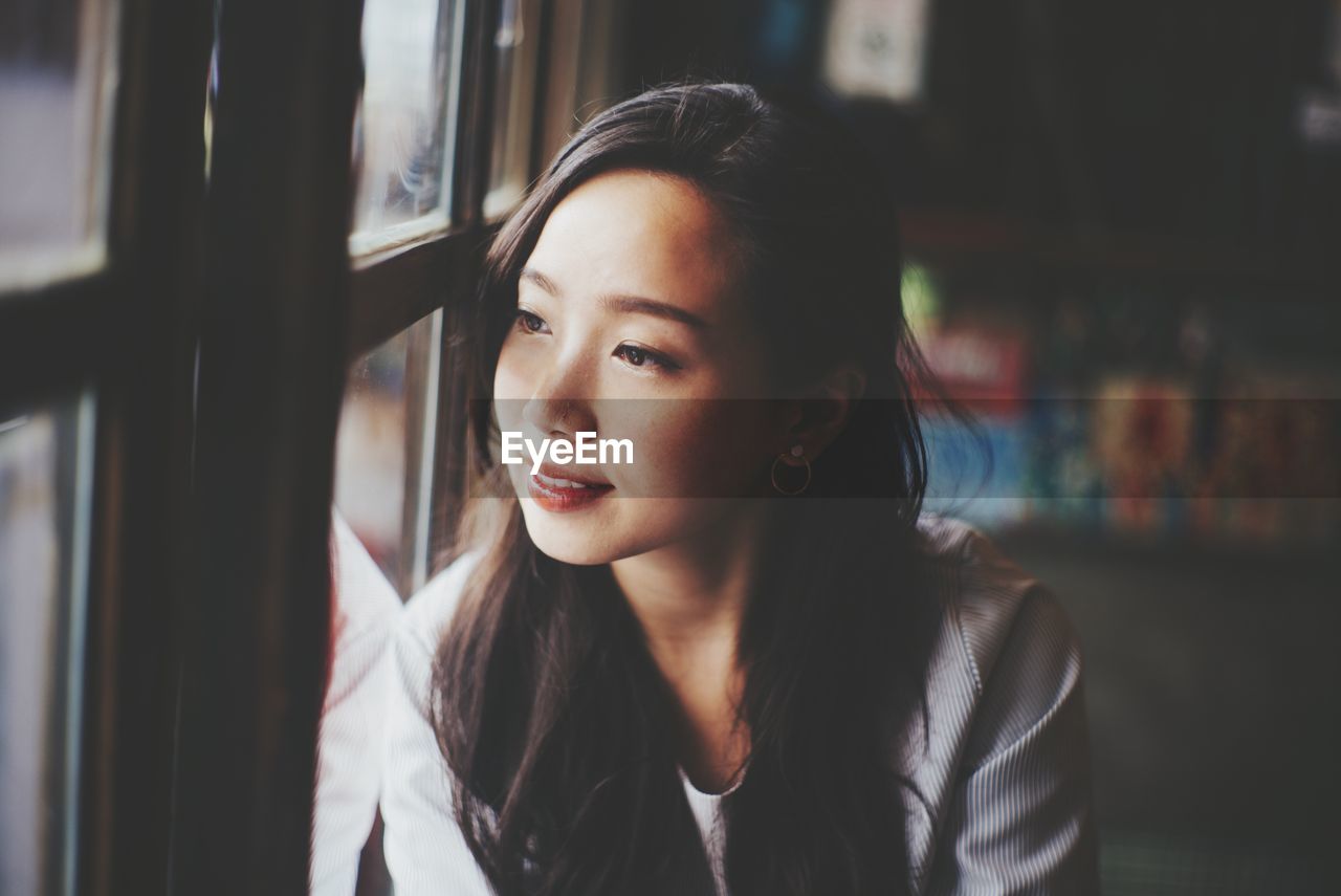 Portrait of young woman looking through window