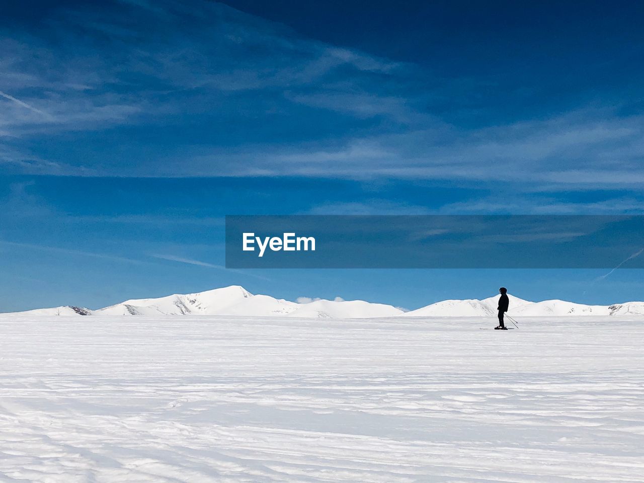 Woman skiing on snow covered land against sky