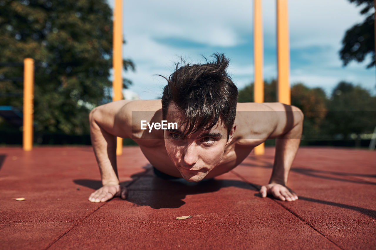 Shirtless man exercising on floor outdoors