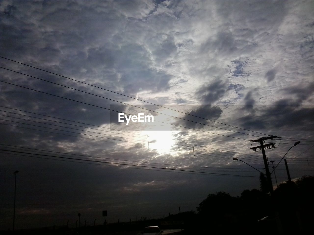 Low angle view of electricity pylon against cloudy sky