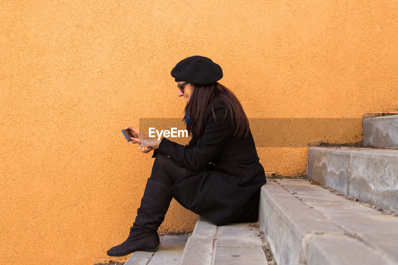 SIDE VIEW OF MAN USING PHONE ON WALL