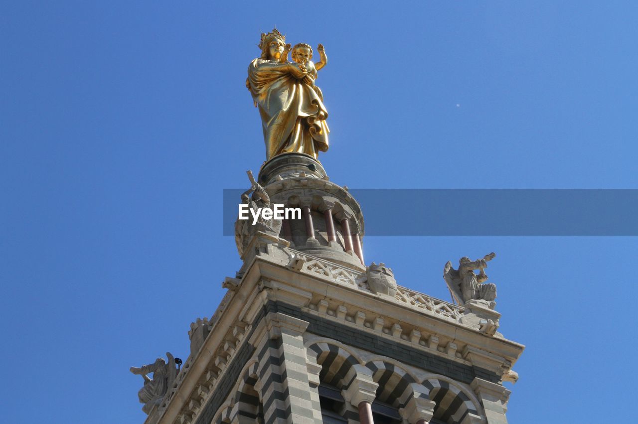Low angle view of virgin mary and jesus christ sculptures on top of notre dame de la garde