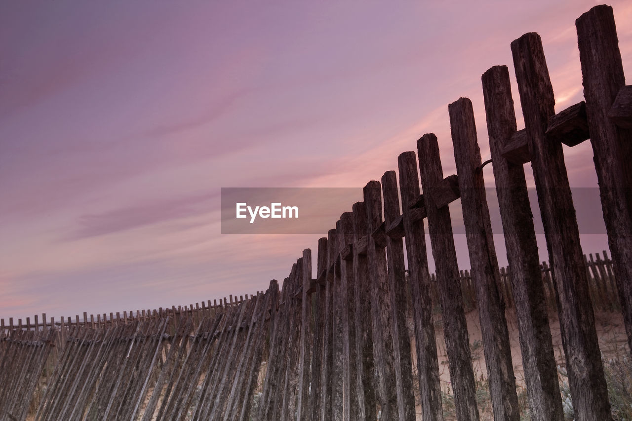 LOW ANGLE VIEW OF WOODEN POSTS ON LANDSCAPE AGAINST SKY