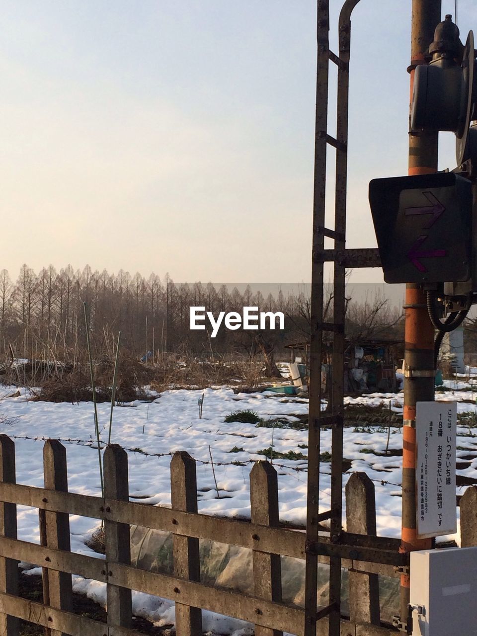 Wooden fence on snow covered field against clear sky