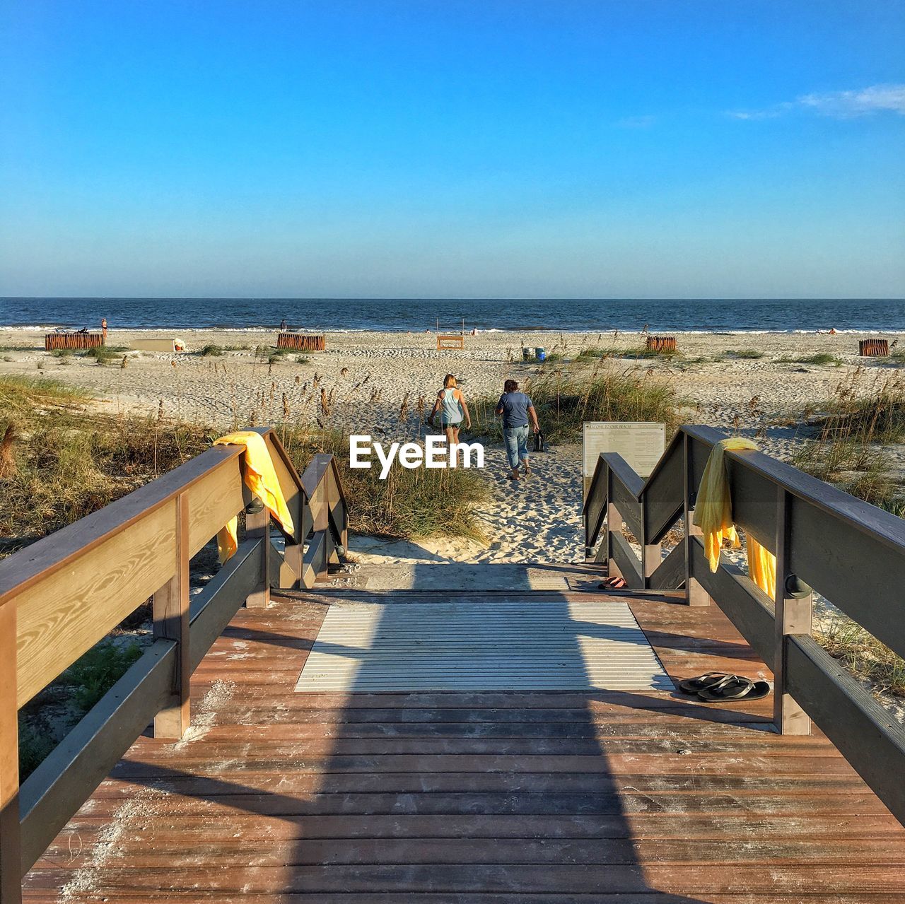 REAR VIEW OF WOMAN WALKING BY SEA AGAINST CLEAR SKY