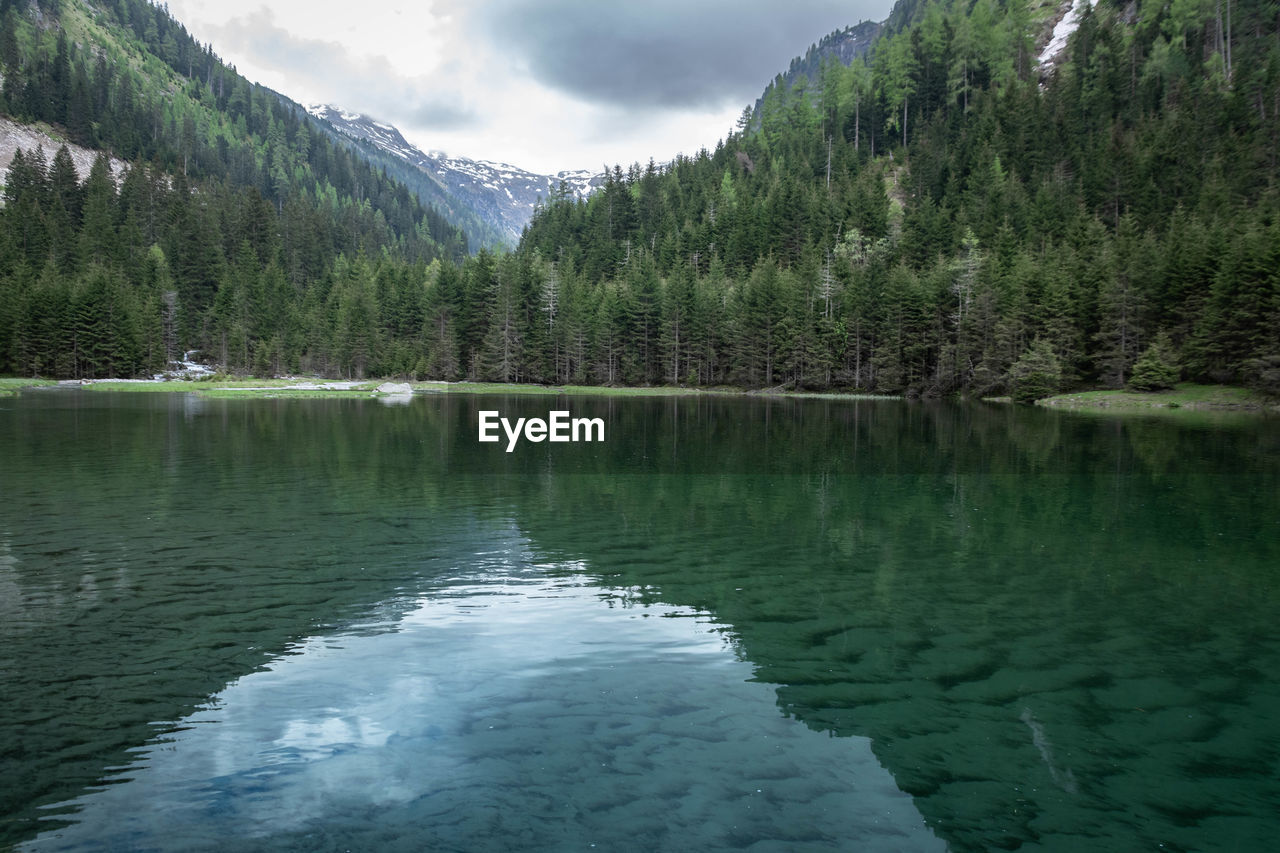 scenic view of lake by mountains against sky