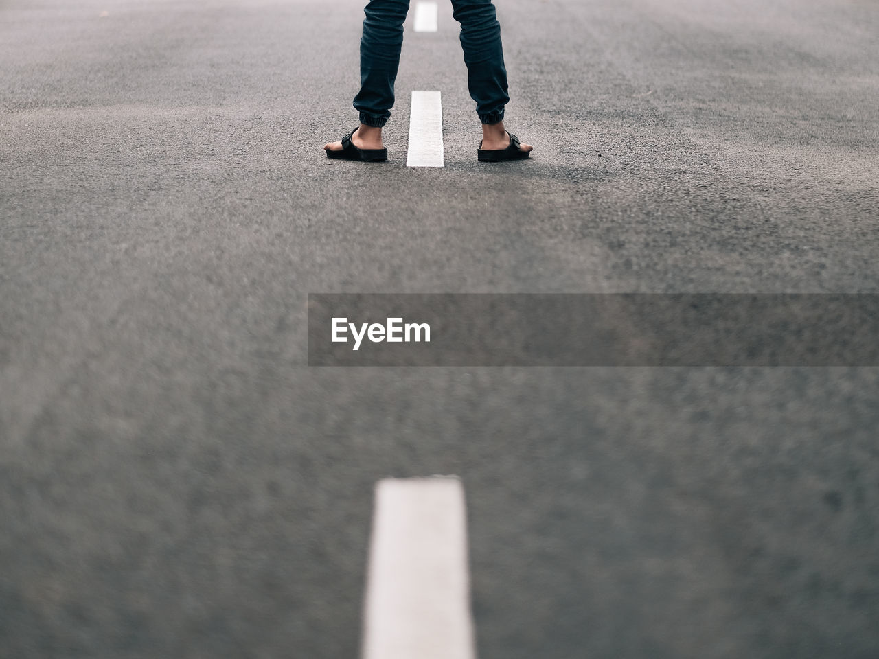 A boy standing in the middle of an empty road