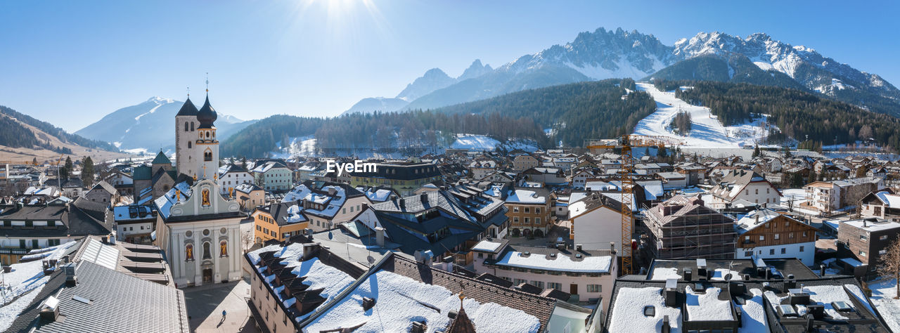 Panoramic view of town against mountains on sunny day during winter