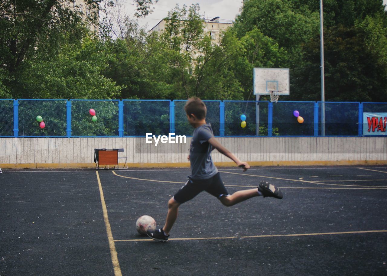 FULL LENGTH OF A BOY PLAYING WITH BALL IN THE FOREST