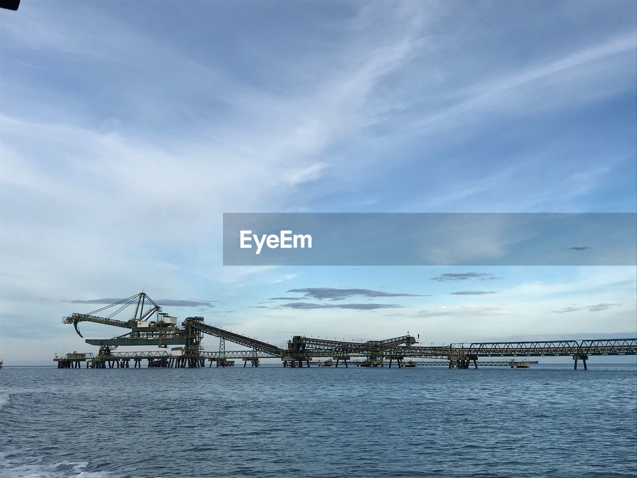 CRANES AT PIER AGAINST SKY