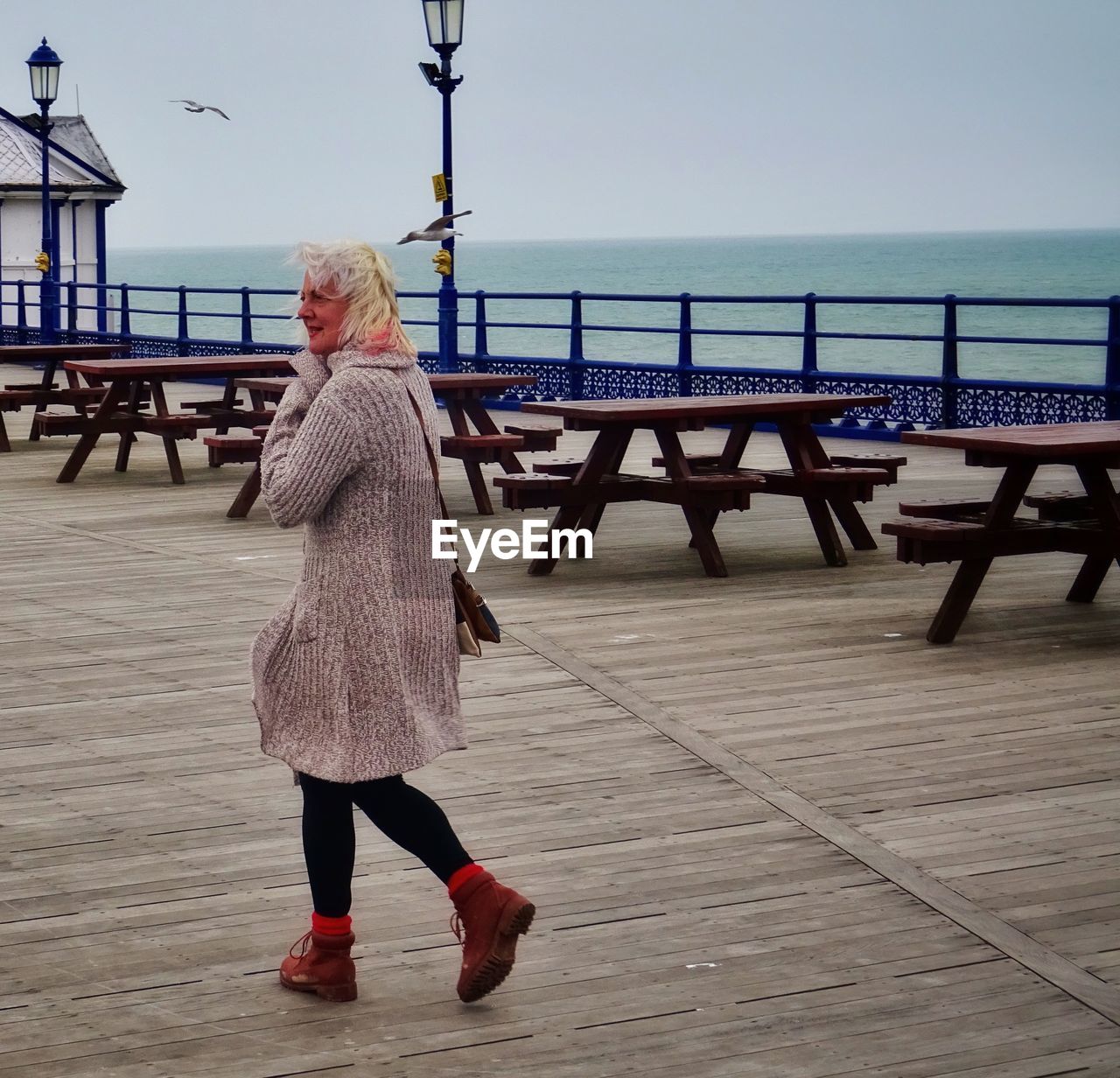 Woman walking on pier against sky