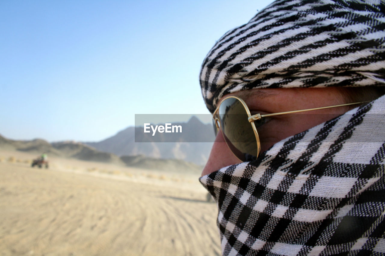 Close-up of man in desert against clear sky