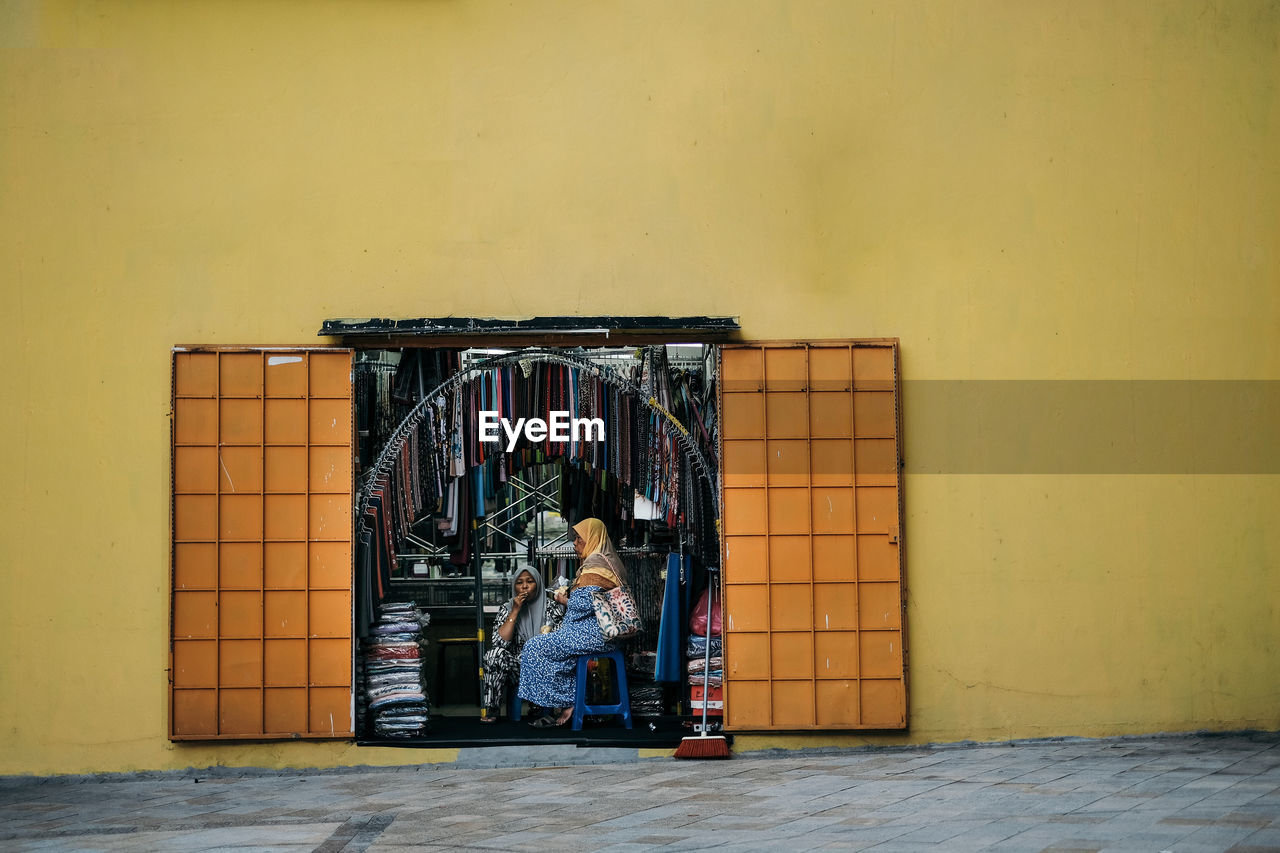 MAN SITTING ON WALL OF BUILDING