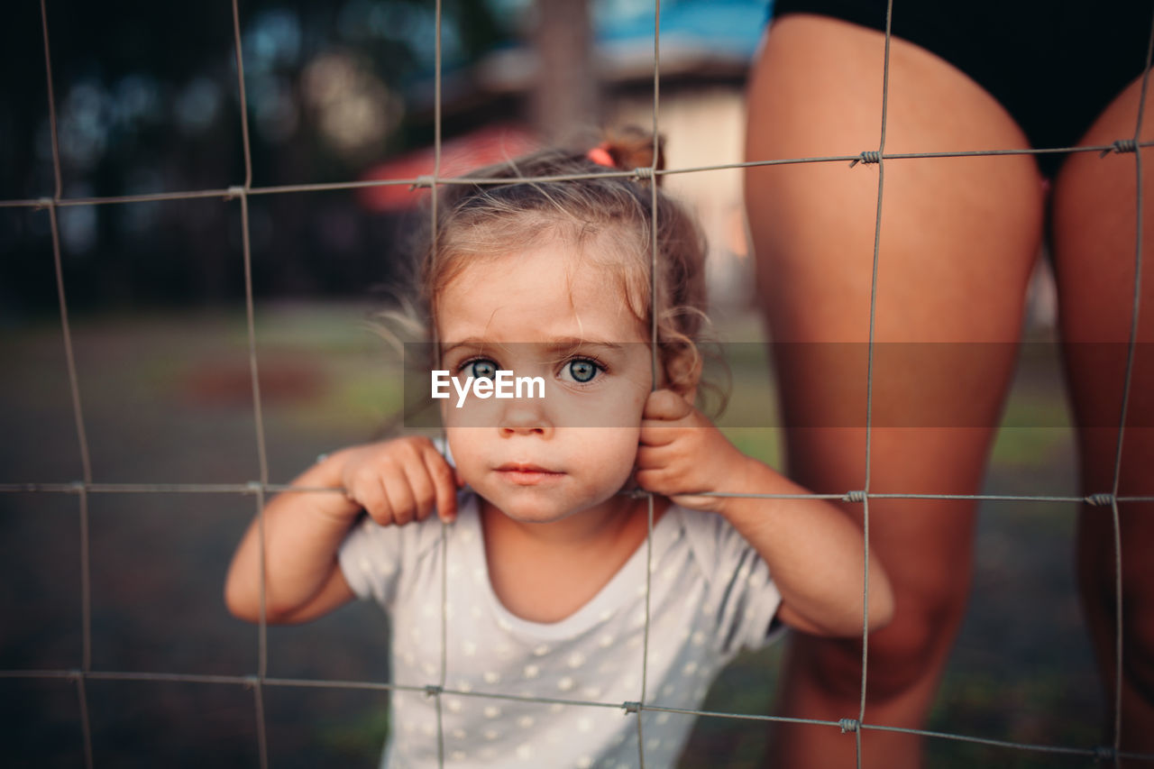 Portrait of cute girl standing by fence