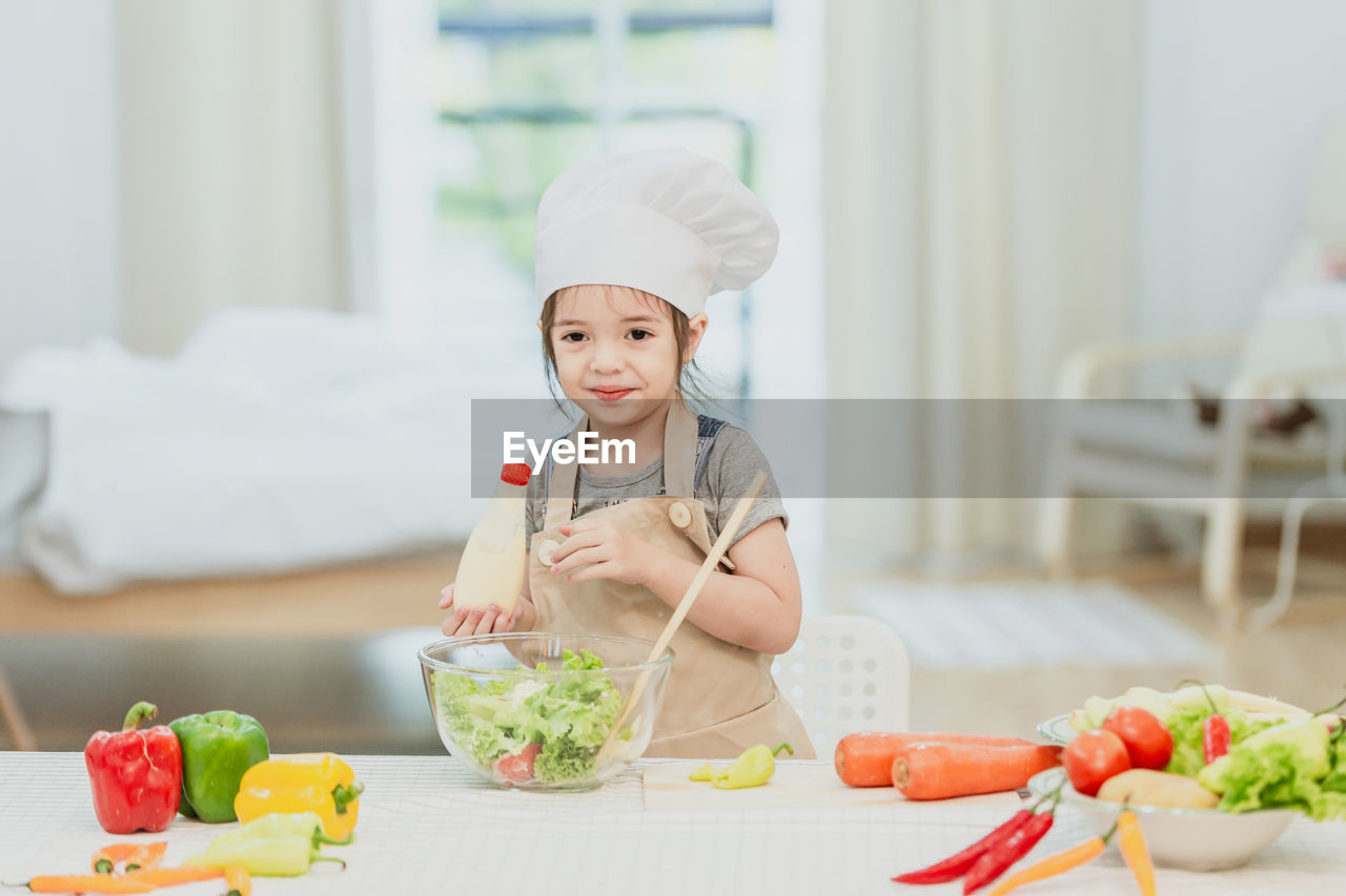 Happy family mom teaching cute girl preparing and cooking healthy salad for the first time.