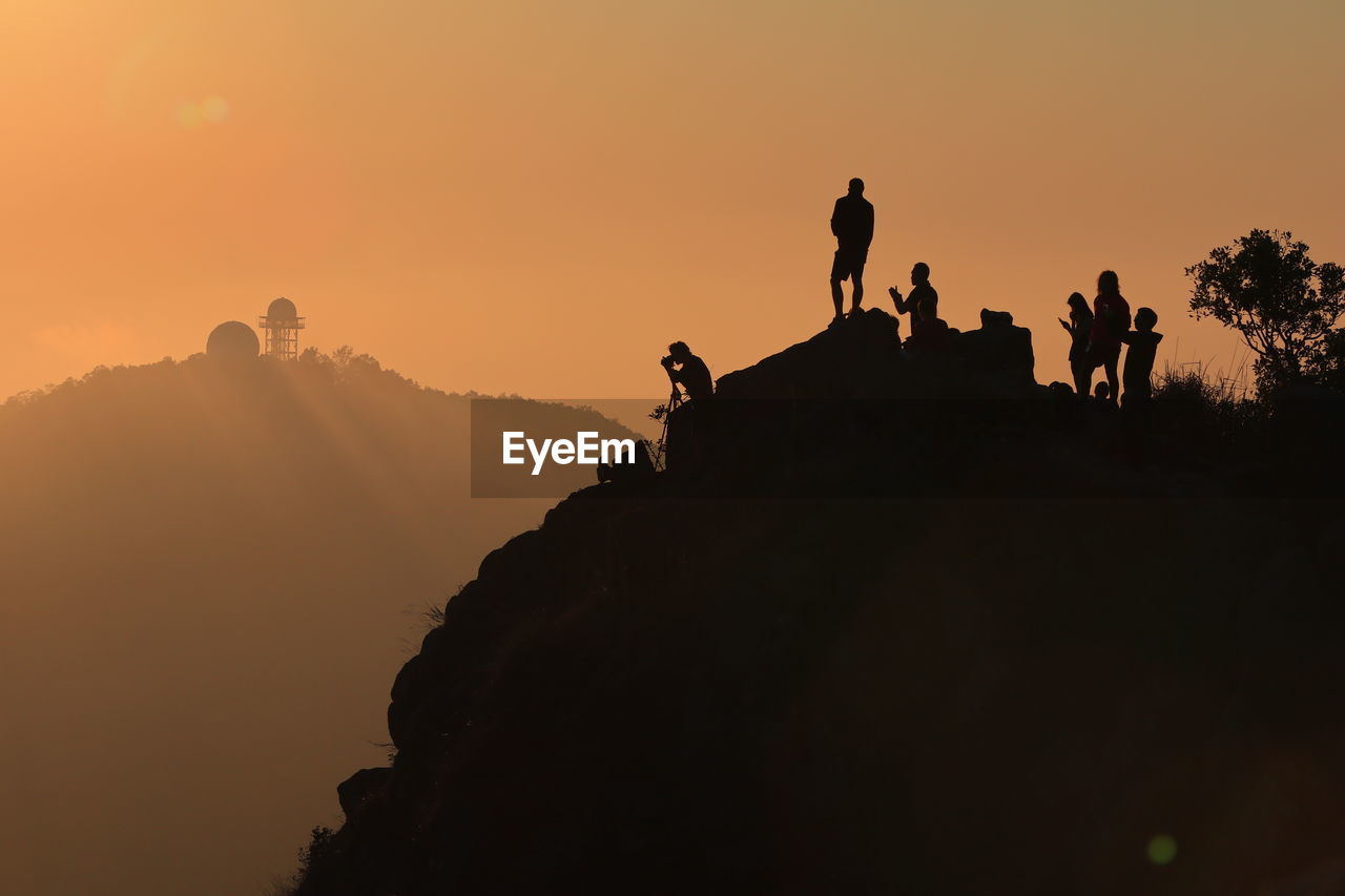 Silhouette man on mountain during sunset