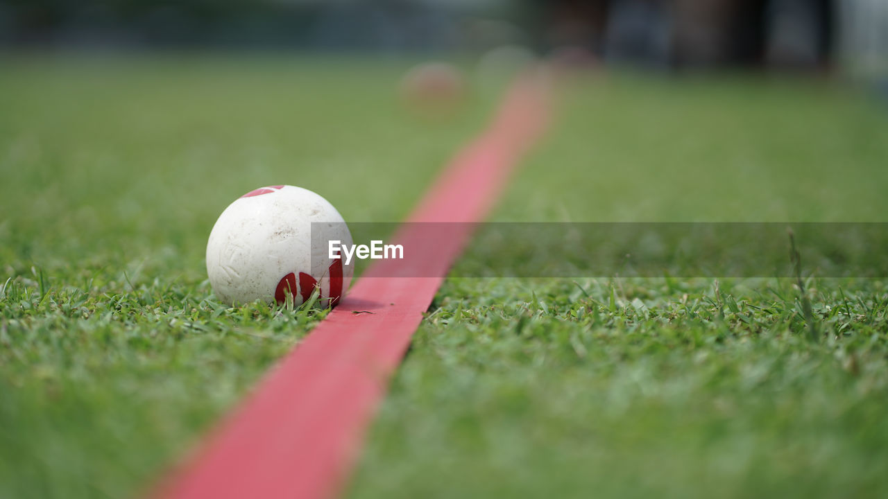 CLOSE-UP OF BALL ON FIELD BY GRASS