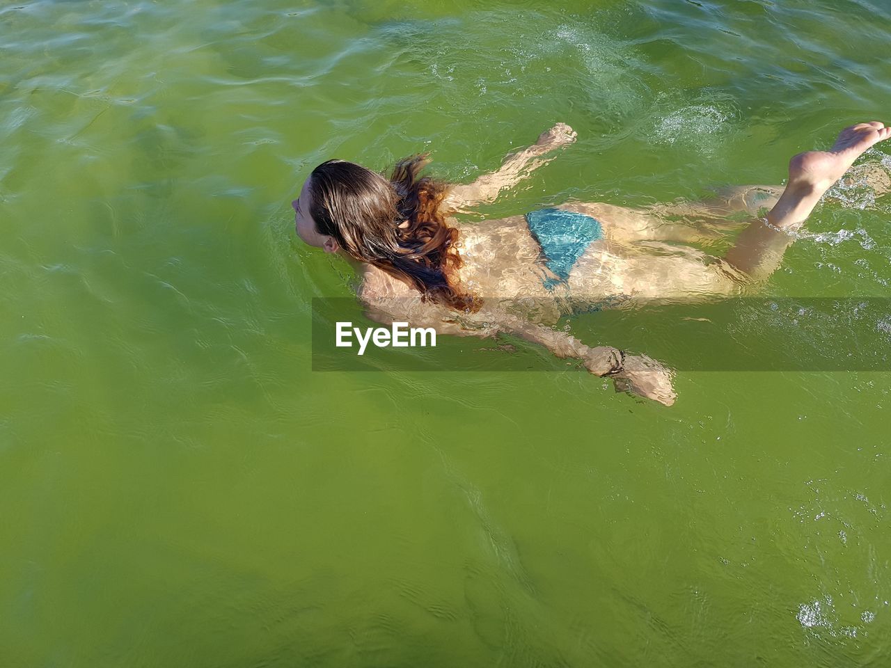 HIGH ANGLE VIEW OF WOMAN SWIMMING IN SEA WATER