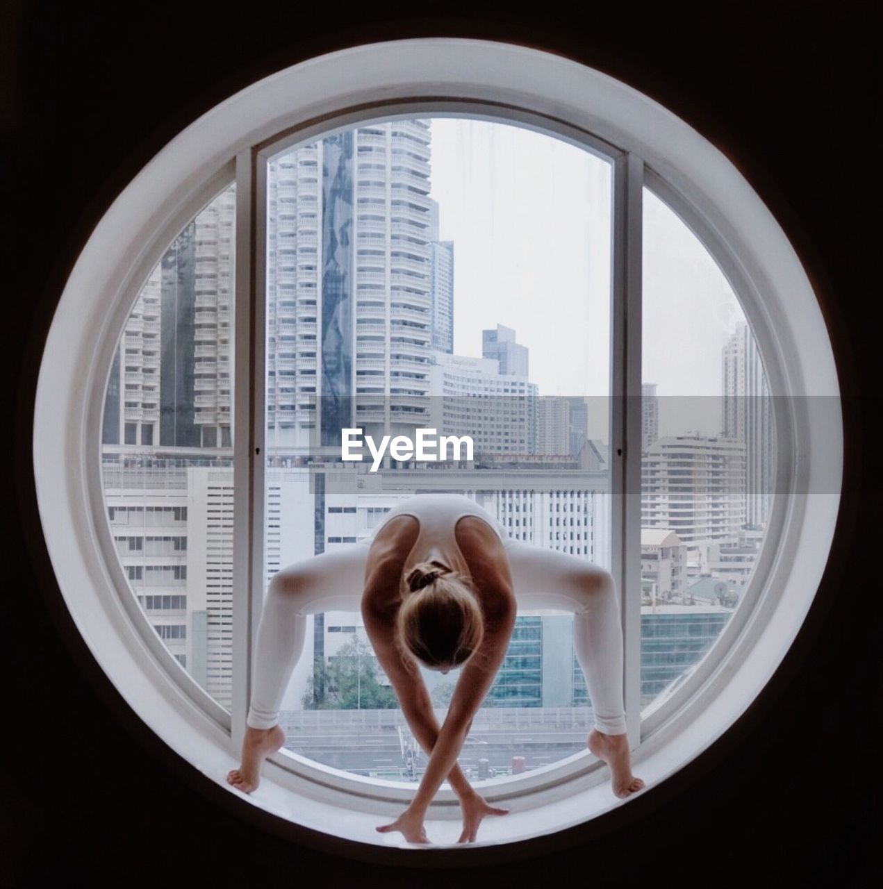Full length of woman practicing yoga at circular window