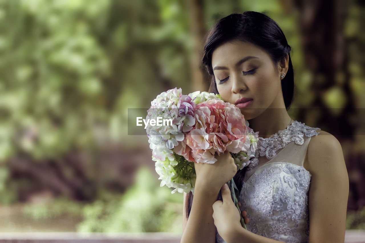 Bride holding flower bouquet with eyes closed