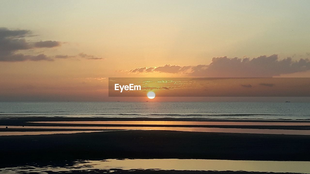 SCENIC VIEW OF BEACH AGAINST SKY AT SUNSET