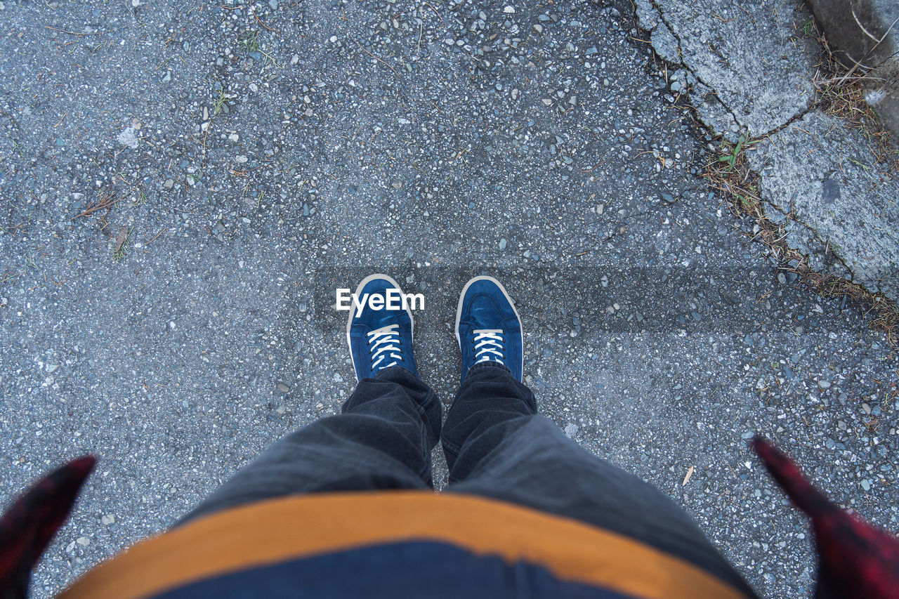 low section, human leg, shoe, blue, personal perspective, one person, high angle view, standing, lifestyles, day, road, street, limb, leisure activity, men, human limb, city, outdoors, nature, directly above, footwear, human foot, casual clothing, jeans, transportation, clothing, black