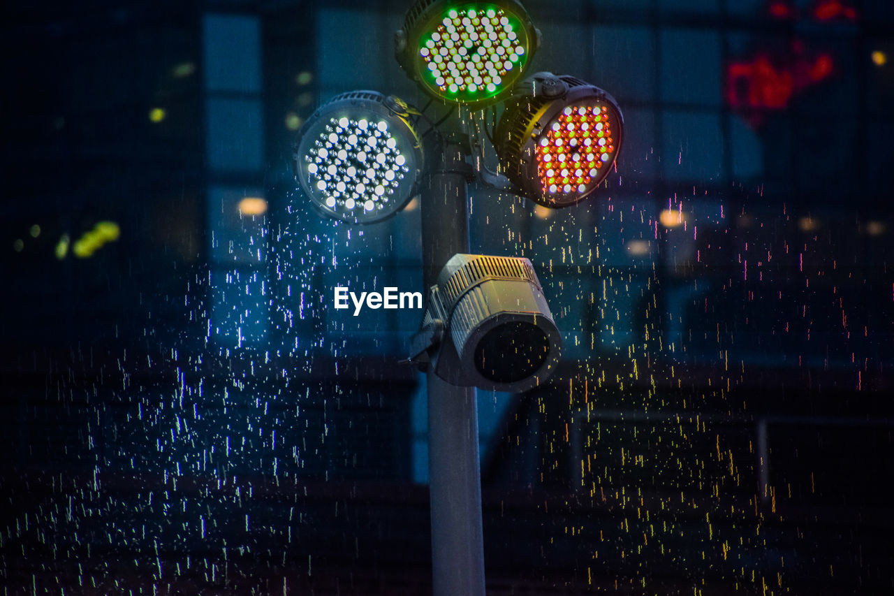 Illuminated lights on wet street at night