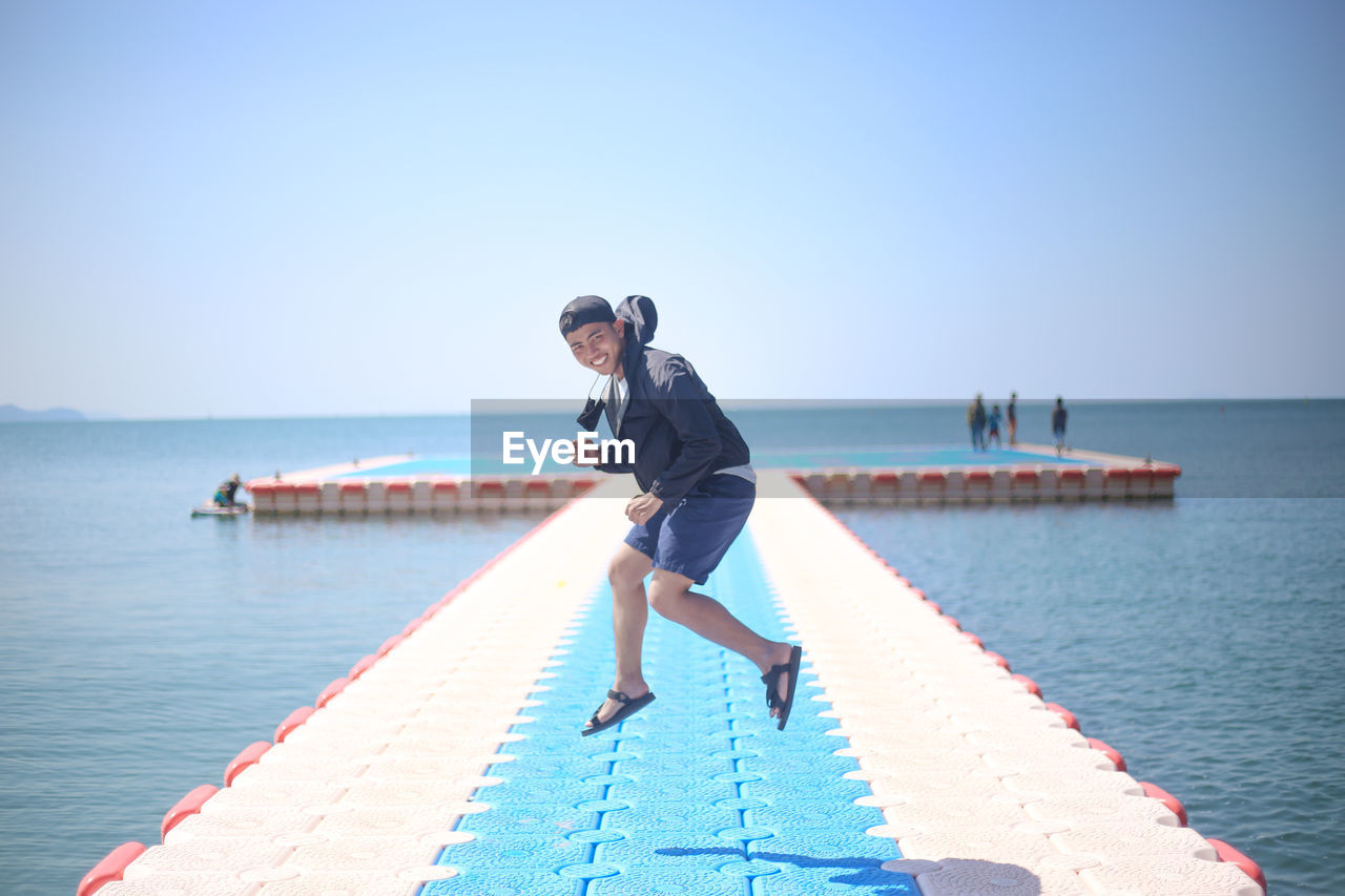 Man on pier over sea against clear sky