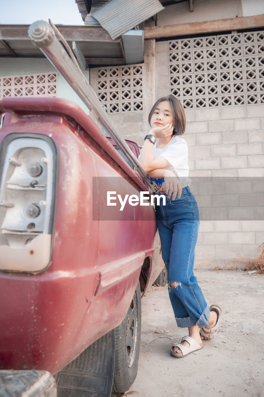 Portrait of young woman sitting on car