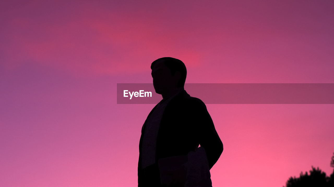 SILHOUETTE MAN STANDING AGAINST PINK SUNSET SKY